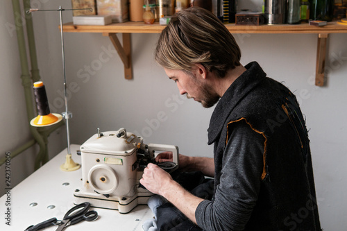 Man tailor working on furrier machine in workshop photo