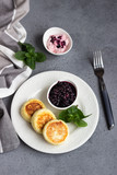 Cottage cheese pancakes or fritters with blueberry sauce and mint. Traditional Ukrainian and Russian cuisine. Syrniki. Healthy and diet breakfast.
