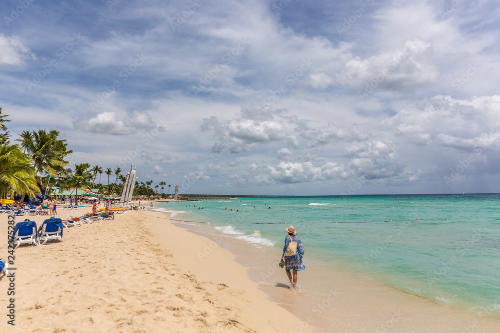 Bayahibe, Dominican Republic - July 22nd 2018 - Lonely woman walking in an amazing blue water in Bayahibe area in Dominican Republic