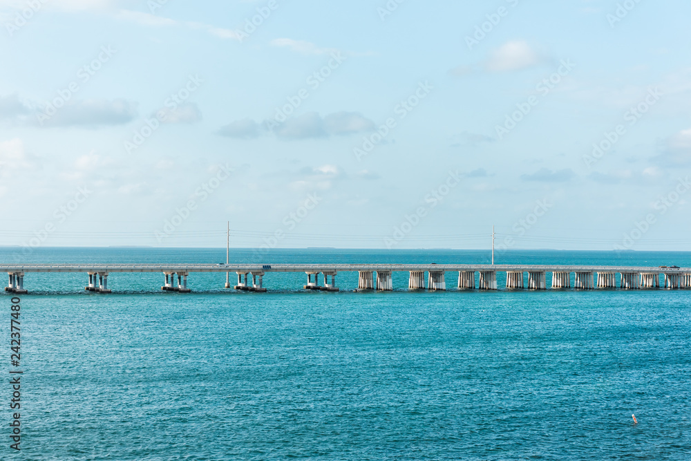 Seven Mile Bridge landscape of Florida Keys turquoise blue water atlantic ocean and cars on Overseas Highway road with horizon clouds