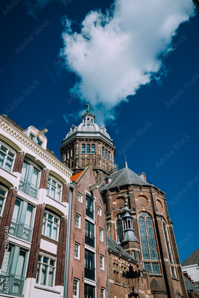 Cathedral in Amsterdam against blue sky and white cloud. Low angle view