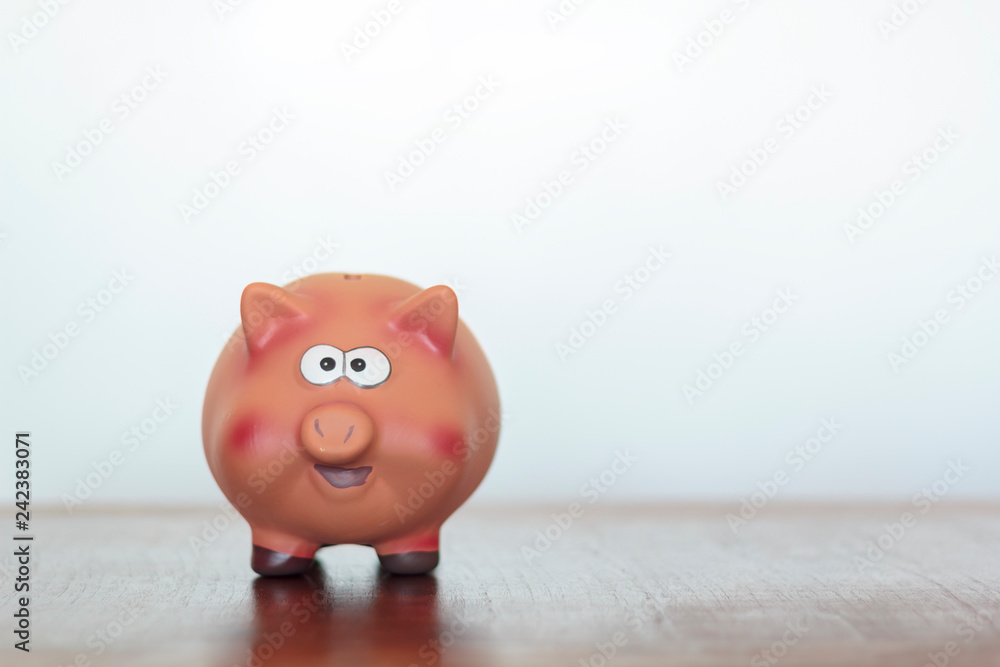 Fototapeta premium Piggy bank on wooden table against white background