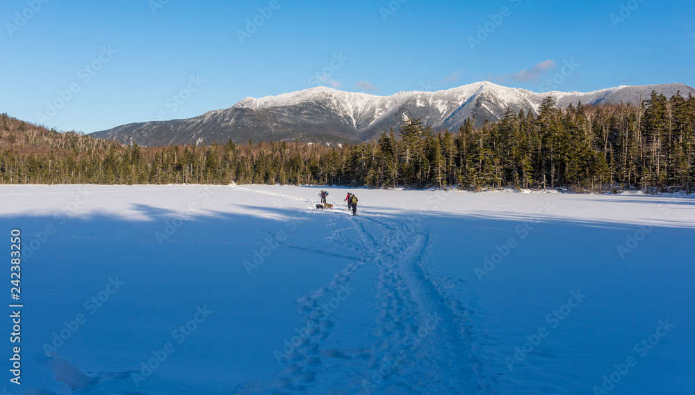 a group of hikers on a cold day walking across a frozen snowy lake