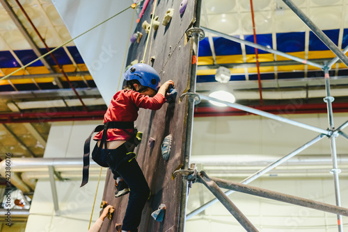 Child on the walls of a climbing wall with the help of a safety rope