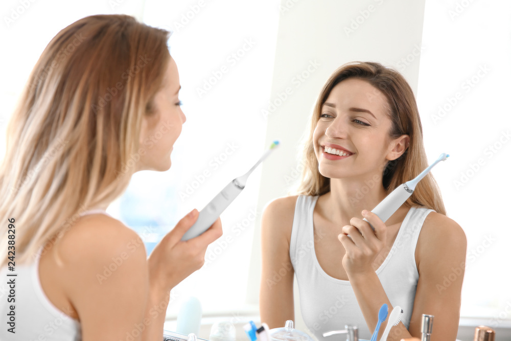 Young beautiful woman with toothbrush near mirror in bathroom. Personal hygiene Young beautiful woman with toothbrush near mirror in bathroom. Personal hygiene