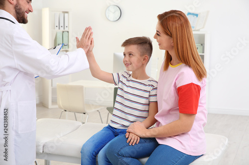 Children s doctor giving high five to patient in hospital