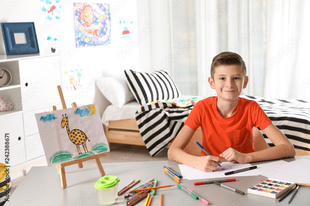 Little child drawing picture at table with painting tools indoors Little child drawing picture at table with painting tools indoors