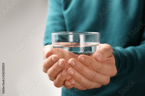 Man holding glass with fresh water against gray background, closeup