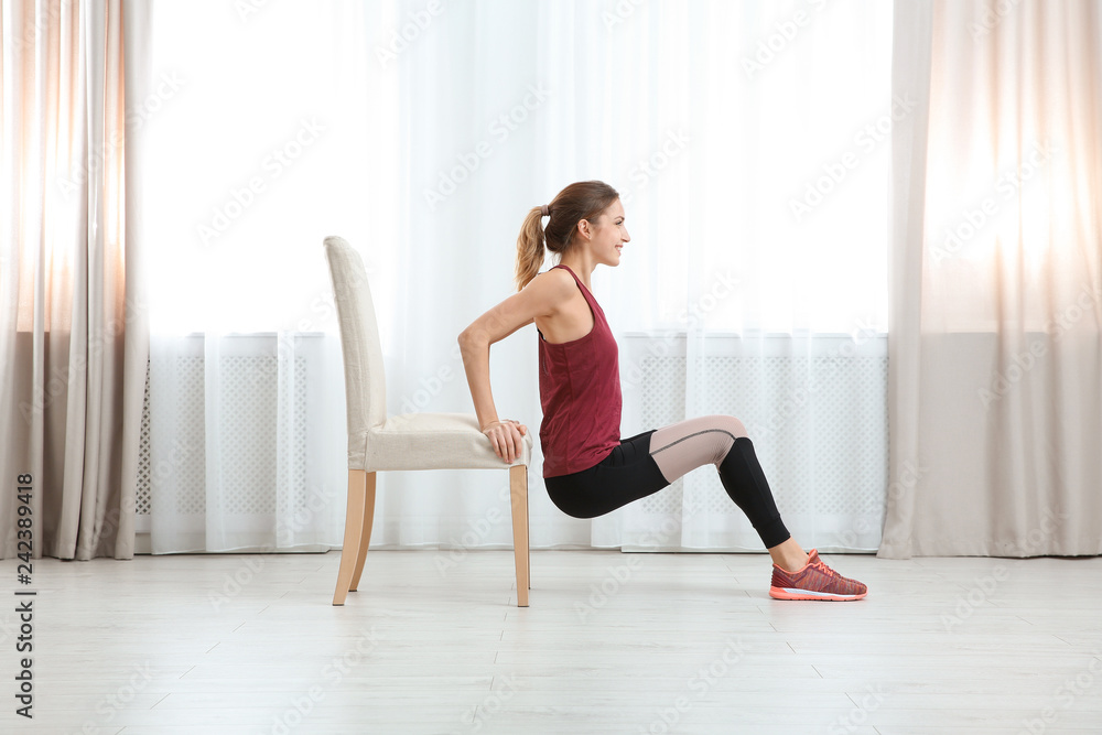 Young woman exercising with chair indoors. Home fitness Young woman exercising with chair indoors. Home fitness