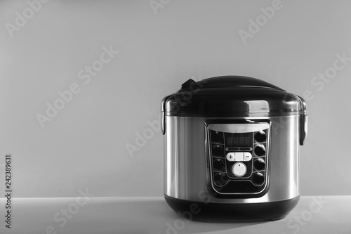 Modern powerful multi cooker on table against grey background. Space for text