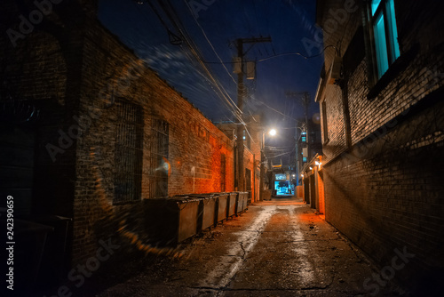 Dark and eerie industrial urban city alley with dumpsters at night in Chicago