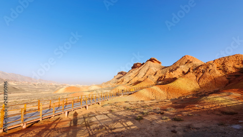 Walking paths around sandstone rock formation at Zhangye National Geological Park. Zhangye Danxia National Geopark, Gansu, China. Colorful landscape of rainbow mountains with blue sky background. © atiger