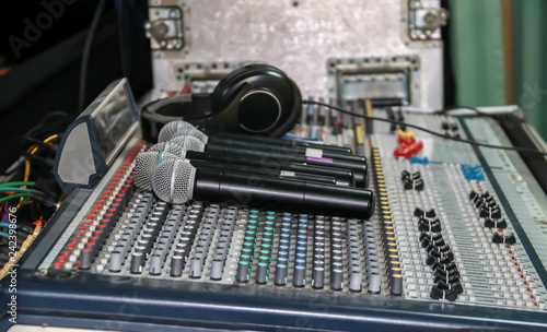 Close up of wireless microphone and headphone put on sound music mixer control panel. Sound Mixer Equalizer Panel
