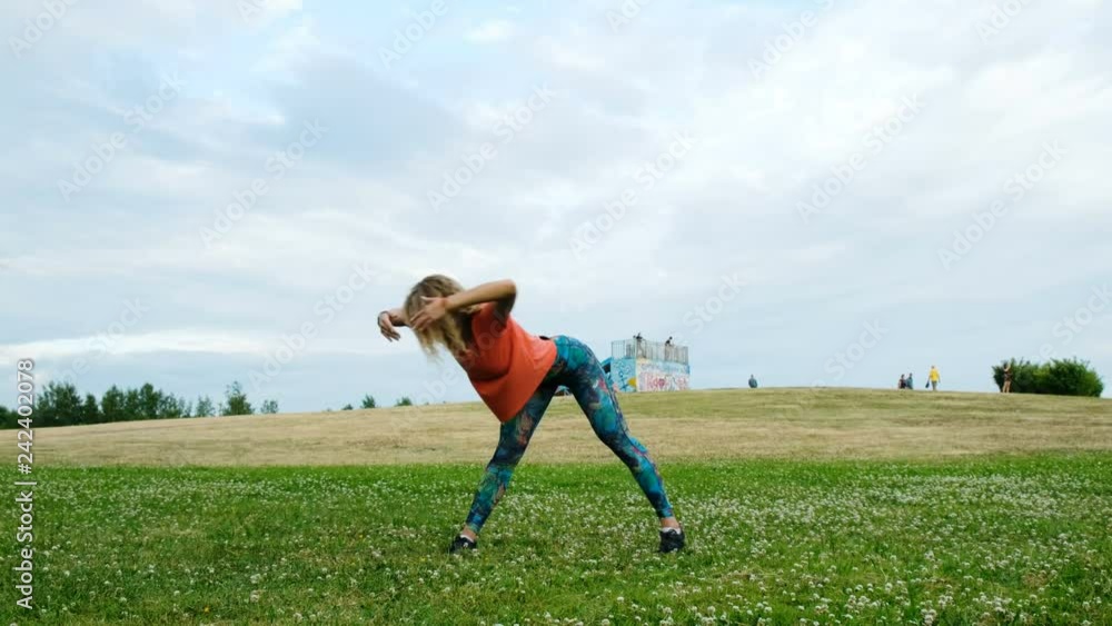 Athletic woman training in a city park in nature, a girl stretches her back and makes sagging Athletic woman training in a city park in nature, a girl stretches her back and makes sagging