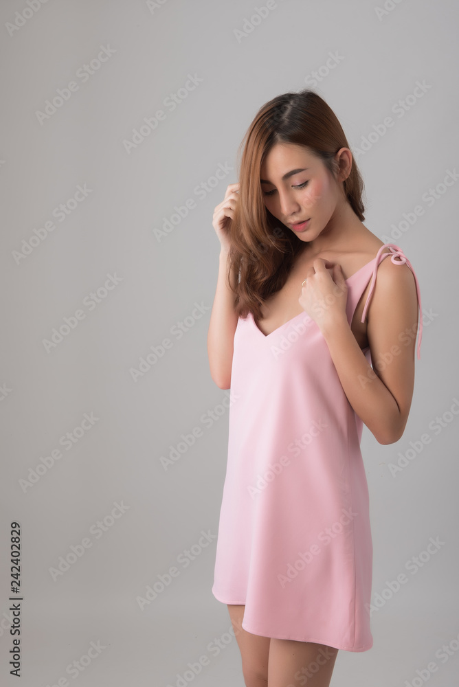 Half length portrait, Asian beautiful woman in pink dress standing over grey background; Cute female model posing in studio; Free from copy space. Half length portrait, Asian beautiful woman in pink dress standing over grey background; Cute female model posing in studio; Free from copy space.