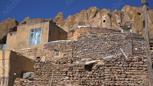 Steady, wide, exterior, daytime shot of homes and stone walls in the Kandovan Village.