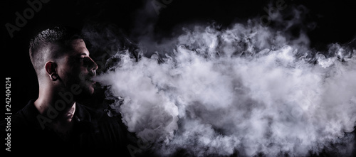 Man blowing a lot of smoke from vaping. Wide format photo.