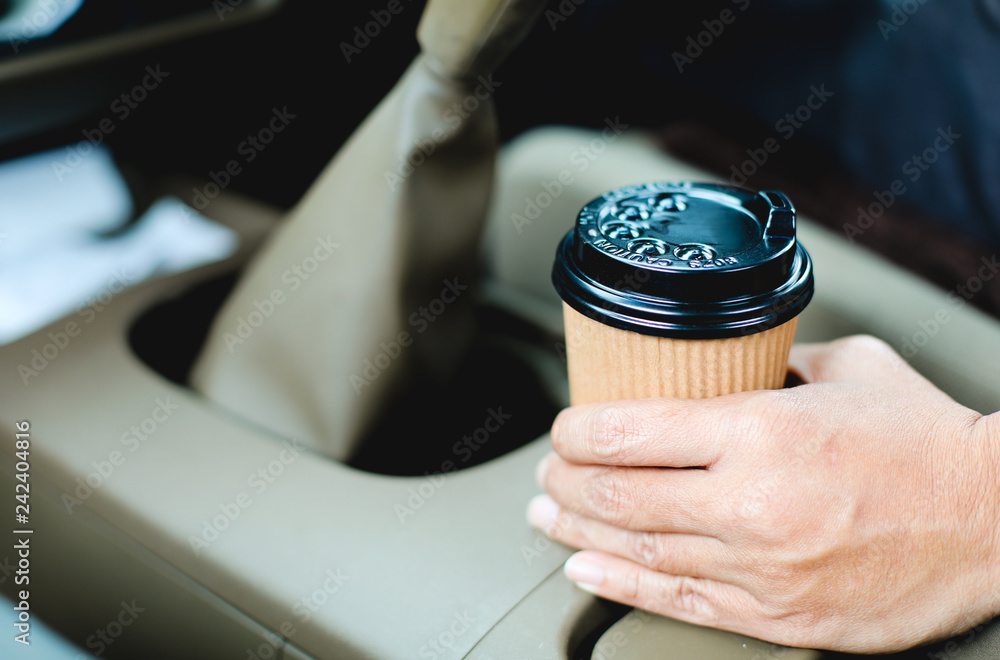 Close up driver holding a cup of coffee in the car.