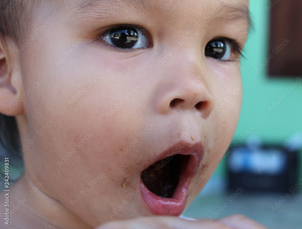 Asian little child girl open her mouth to show snacks inside. Asian little child girl open her mouth to show snacks inside.
