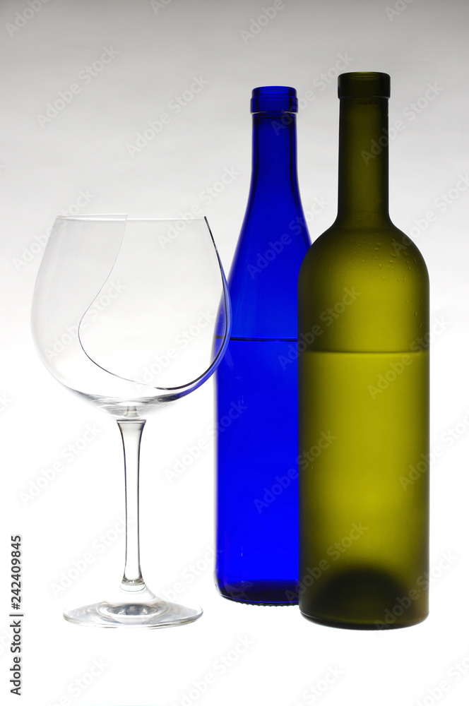 Glass of wine and bottles on light gray Glass of wine and bottles on light gray