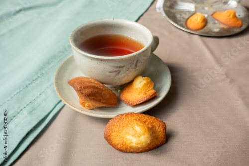 Golden homemade Madeleines cakes with baking mold and cup of tea