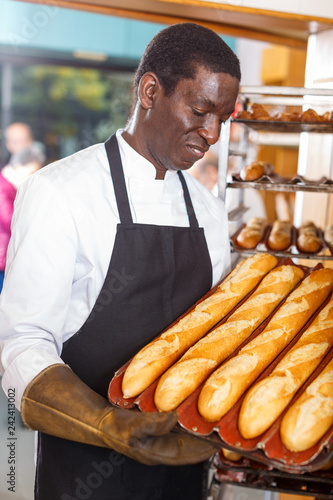 Baker showing tray of fresh bread