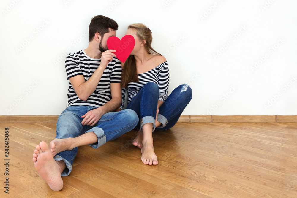 Happy valentines couple sitting on a wooden floor Happy valentines couple sitting on a wooden floor