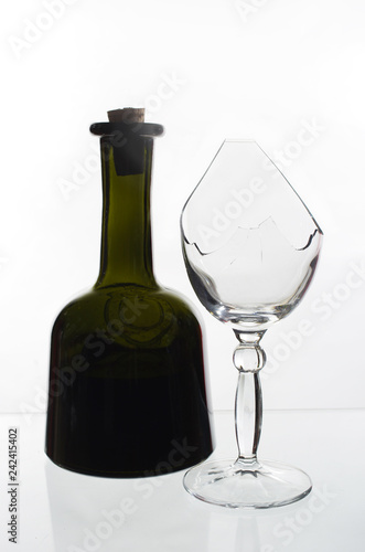 Bottle of wine and a broken glass on a light background