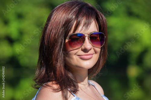 Close up portrait of young woman dressed on checkered pattern dress. Forest and lake background.