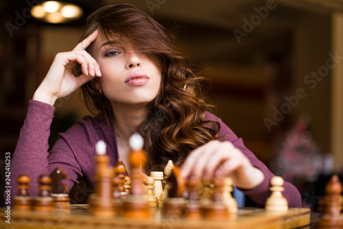 Woman playing chess indoor and thinking position, find winning move, strategy