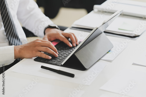 Business man working on tablet computer on white desk in office