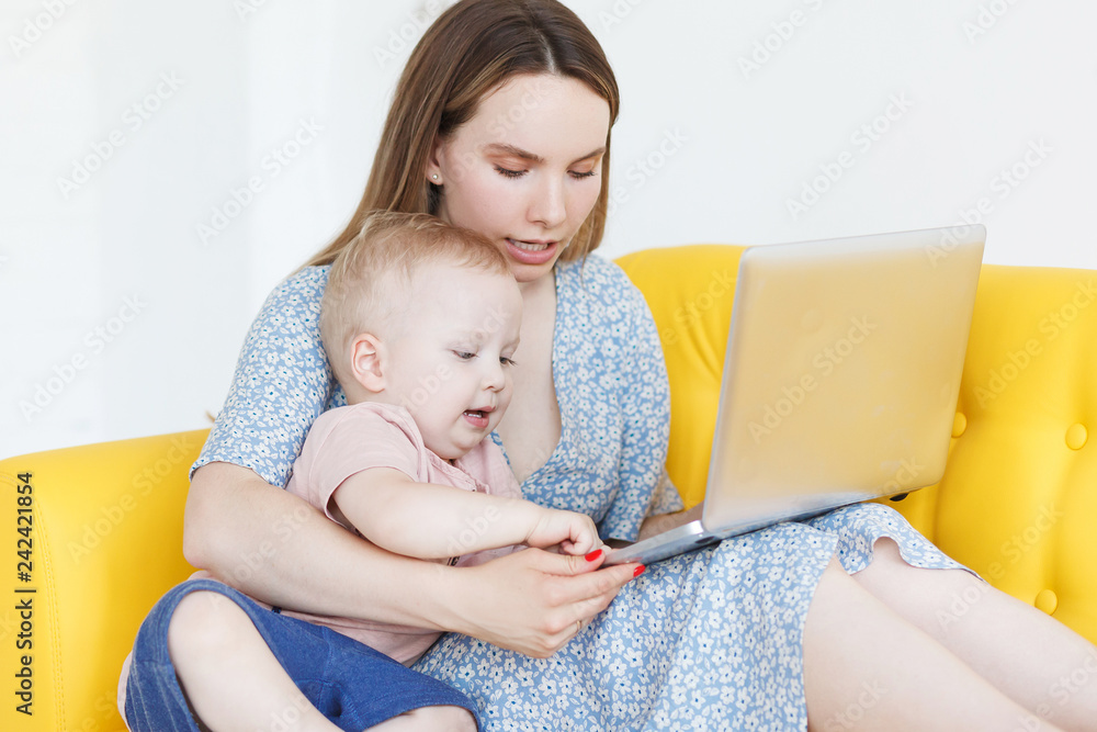Portrait of a beautiful young mother and a clever little son watching developing children's programs and sitting on a sofa in a modern home interior Portrait of a beautiful young mother and a clever little son watching developing children's programs and sitting on a sofa in a modern home interior