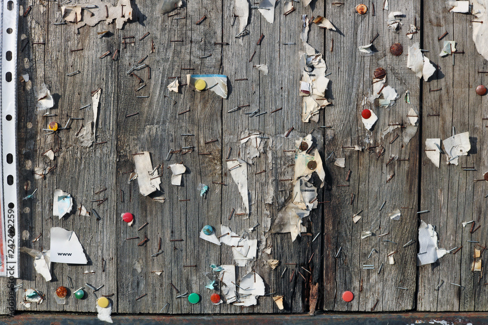 Φωτογραφία Brackets, buttons, nails and pieces of paper on a street wooden bulletin board