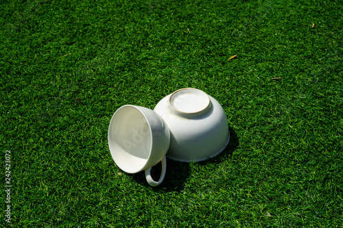 The white ceramic cups for tea and coffee on the green grass.