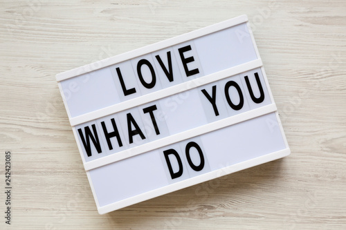 Modern board with text 'Love what you do' over white wooden background, top view. Business concept. From above, flat-lay, overhead.