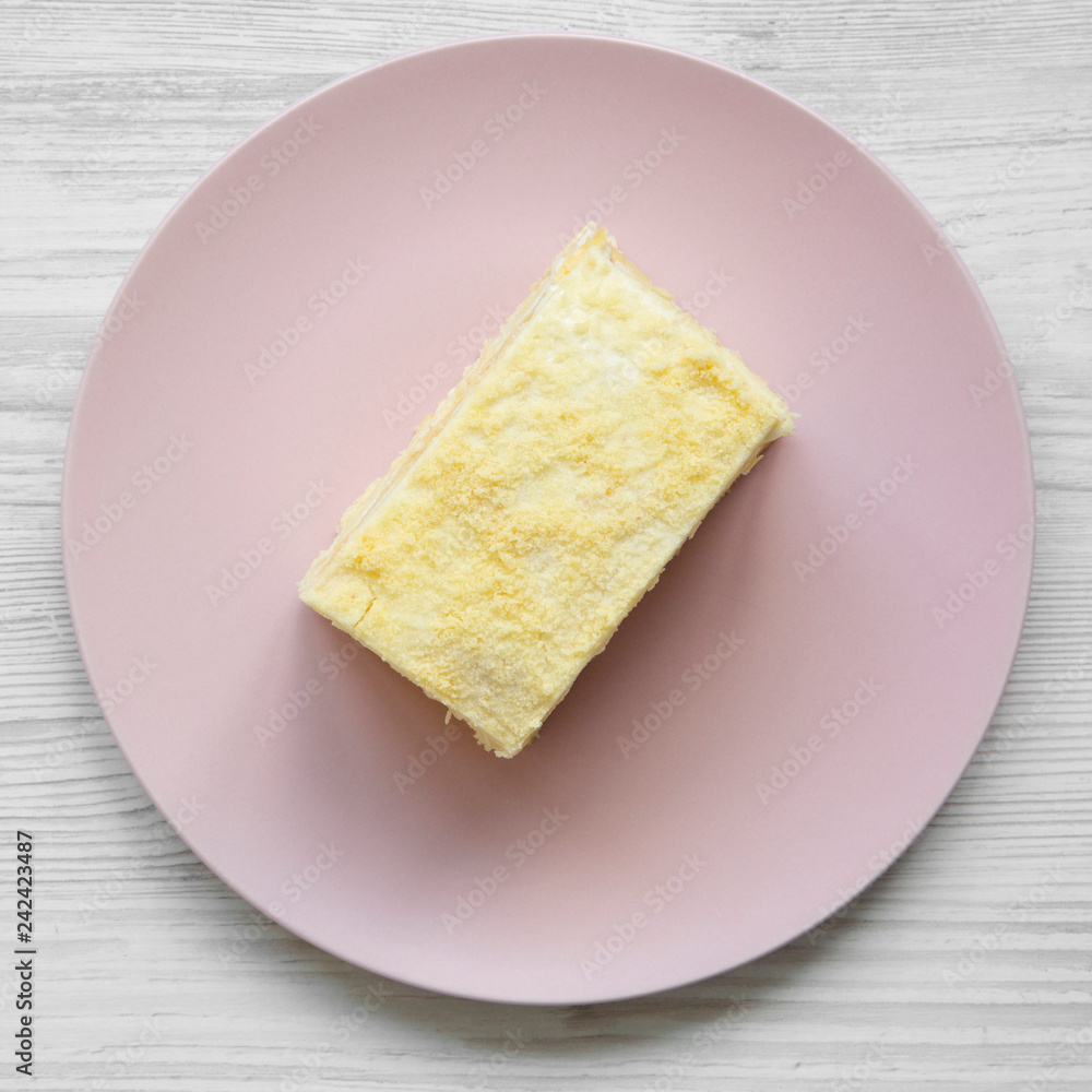 Piece of Napoleon Cake on pink plate over white wooden surface, overhead view. Flat lay, from above. Piece of Napoleon Cake on pink plate over white wooden surface, overhead view. Flat lay, from above.