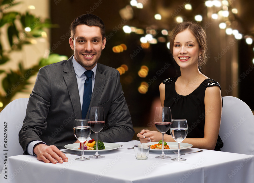 people and leisure concept - smiling couple with food and non-alcoholic red wine at restaurant over festive lights on background people and leisure concept - smiling couple with food and non-alcoholic red wine at restaurant over festive lights on background