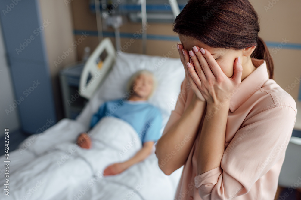 selective focus of crying daughter with sick mother in bed on background in hospital selective focus of crying daughter with sick mother in bed on background in hospital