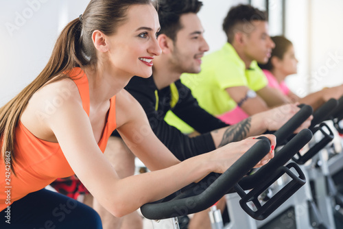 Side view of a smiling woman exercising on bicycle at the fitness center