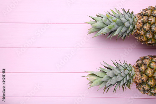 Two ripe pineapples on a pink wooden background