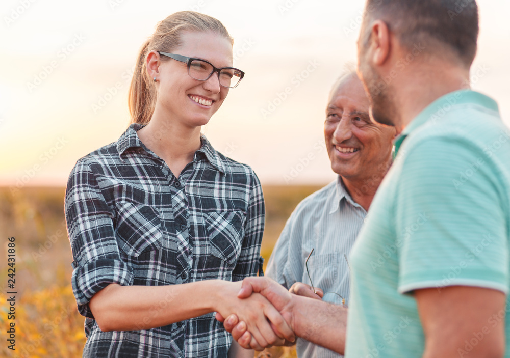 Naklejka premium Handshake for deal, group of farmers standing in a field examining soybean crop before harvesting.