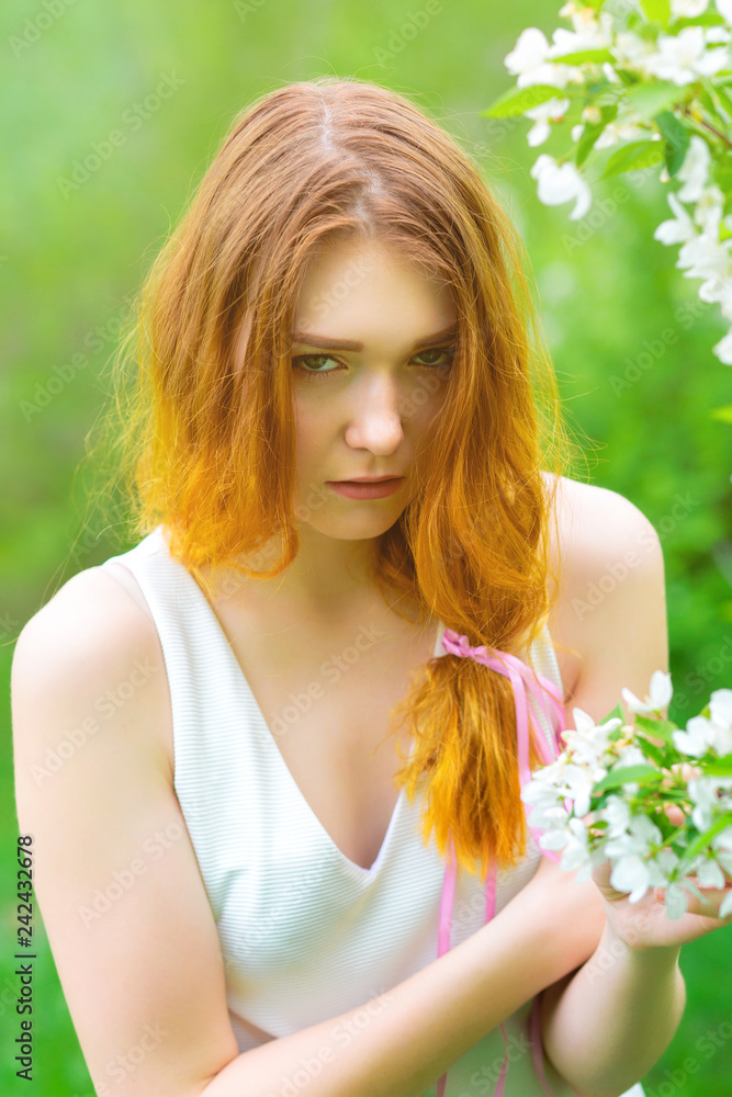 A young girl is photographed near a blooming Apple tree on a background of green grass. The girl and the spring. A young girl is photographed near a blooming Apple tree on a background of green grass. The girl and the spring.
