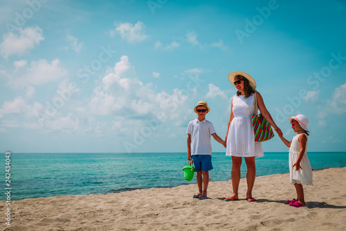 mother with son and daughter walk on beach