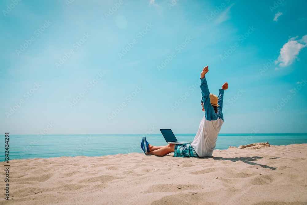 Fotografie young man working on laptop at beach
