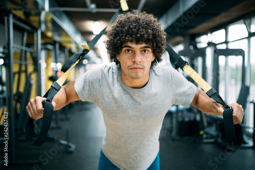 Young handsome man doing exercises in gym