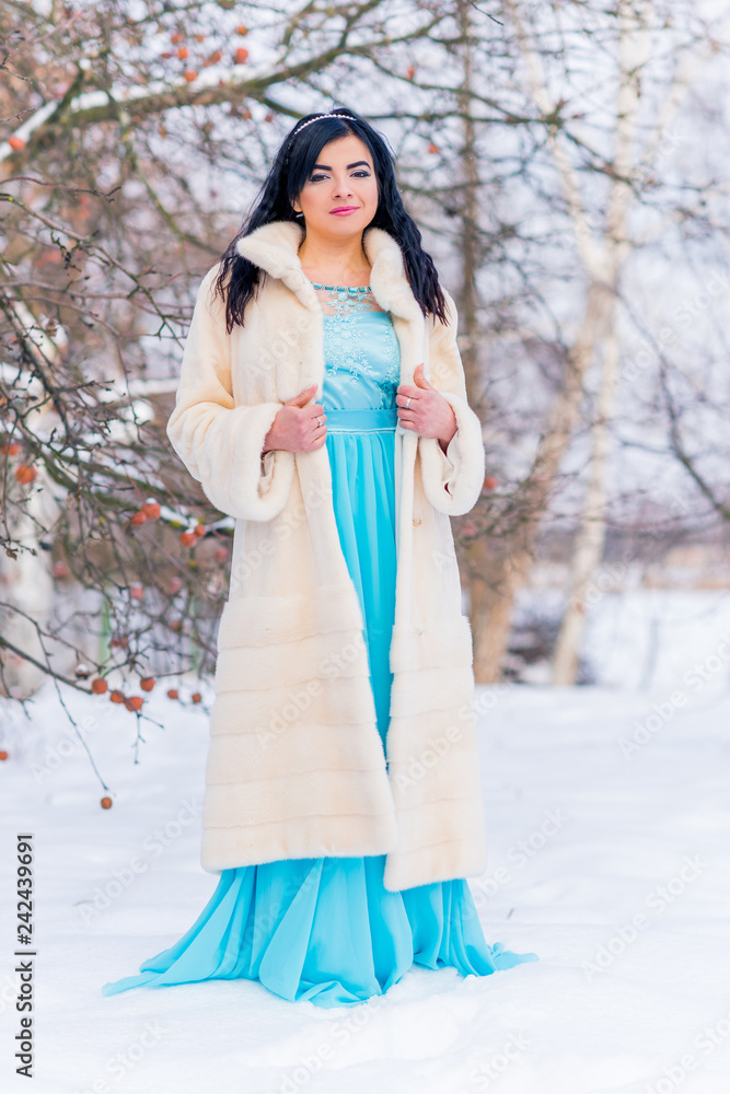 Arabic woman in mink fur coat and blue long romantic dress at snowy day, femininity and grace concept, winter fairytale Arabic woman in mink fur coat and blue long romantic dress at snowy day, femininity and grace concept, winter fairytale