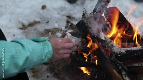 girl makes a fire in winter in the forest