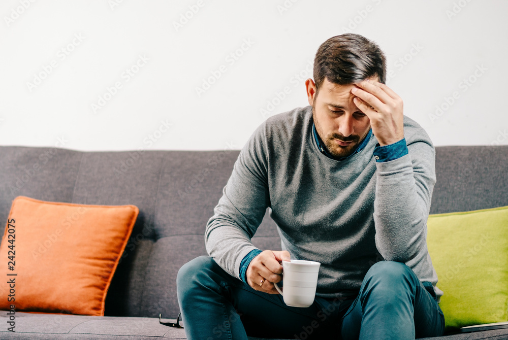 Young man having troubles, sitting at home devastated and worried Young man having troubles, sitting at home devastated and worried