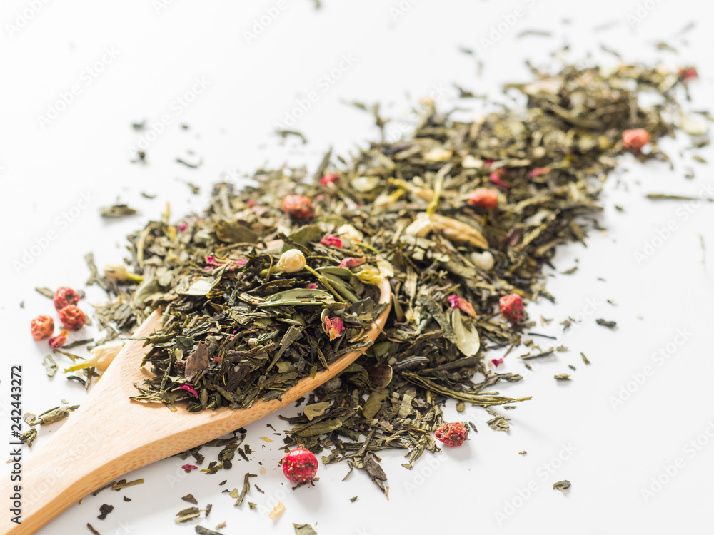 Fototapeta premium Dry leaves of Sencha green flower tea with cowberry leaf, red currant, Jasmine, rose petals, honey granules, forest berry aroma on white background
