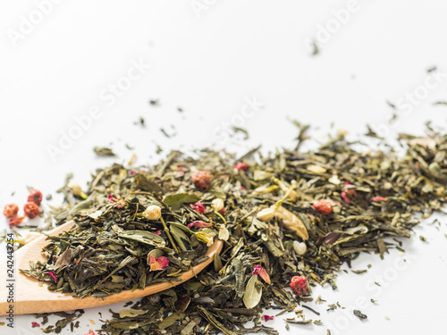 Dry leaves of Sencha green flower tea with cowberry leaf, red currant, Jasmine, rose petals, honey granules, forest berry aroma on white background